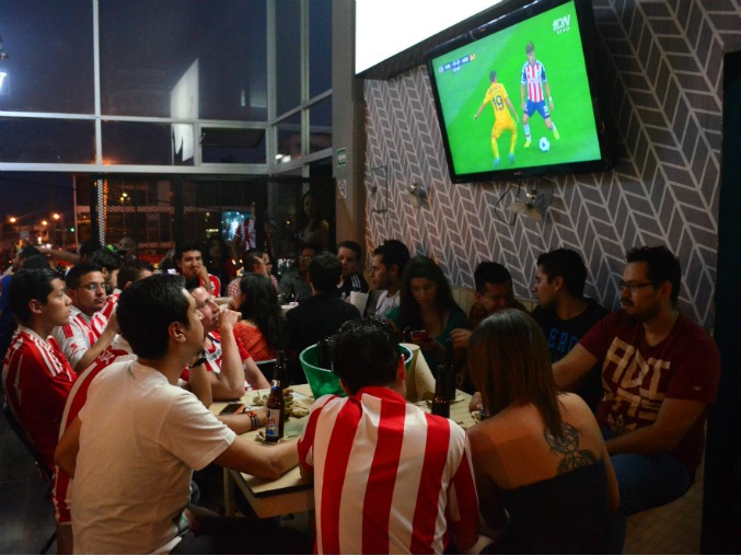 Aficionados de Chivas observan el Clásico en un restaurante