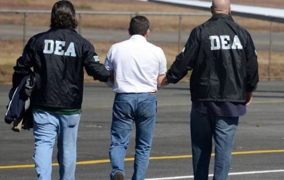 Una persona es trasladada por un par de agentes de la DEA