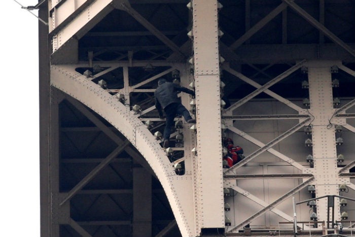 Hombre intentando escalar la torre Eiffel 