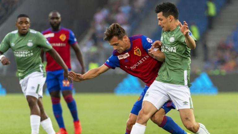 Hirving Lozano peleando un balón ante un jugador del Basel