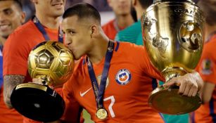 Alexis besa los trofeos obtenidos en la Copa América