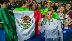 María del Rosario Espinoza posa con su medalla junto a la bandera nacional