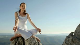 Mujer joven meditando en acantilado