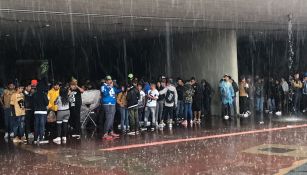 Aficionados de Pumas se cubren de la lluvia bajo un puente