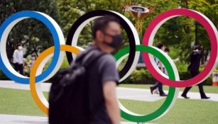 Gente camina junto a los aros olímpicos