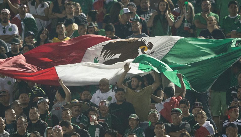 Afición mexicana sosteniendo la bandera azteca