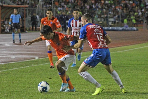 Jugadores de Correcaminos y Chivas disputan un balón