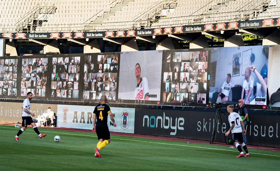 Los jugadores disputan el balón ante la 'mirada' de los aficionados