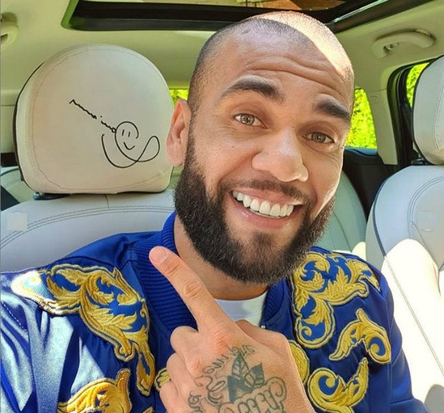 Dani Alves posando con su auto en venta