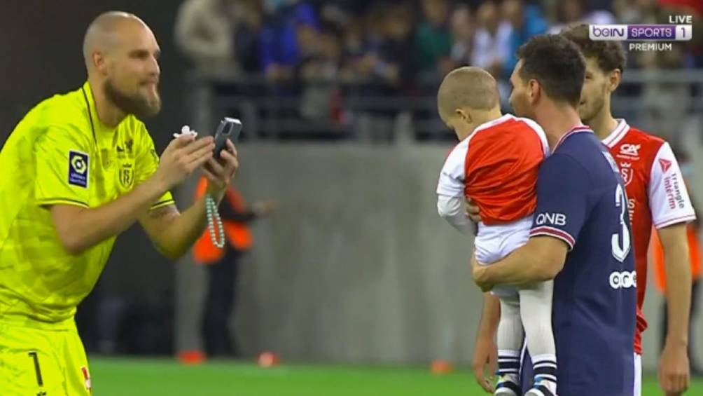 El portero del Reims tomando una foto a su hijo con Messi