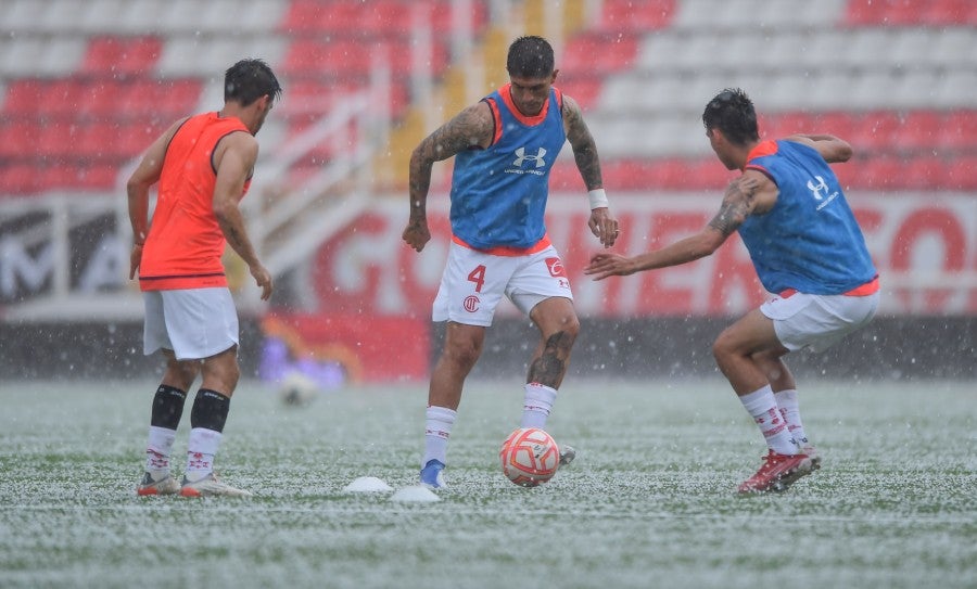 Jugadores calentando en medio de la lluvia