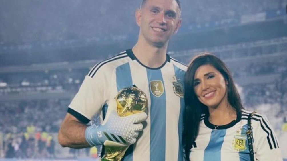 Dibu Martínez con su esposa cargando Copa del Mundo 