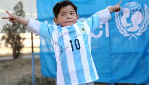 Niño afgano posa con su playera firmada por Messi
