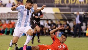 Agüero intenta quitarse una barrida de un jugador chileno