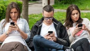 Jóvenes revisando su celular en un parque 