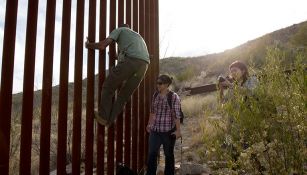 Unos jóvenes intentan cruzar el muro fronterizo