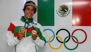 Jhony Corzo sostiene sus medallas junto a los aros olímpicos