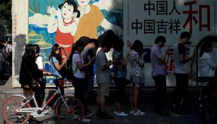 Ciudadanos Chinos hacen fila mientras observan sus smartphones