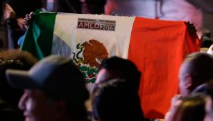 Persona lleva bandera de México con estampa de AMLO