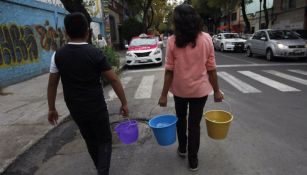 Personas cargando cubetas con agua en la Ciudad de México