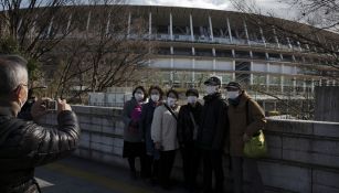 Aficionados japoneses se toman una foto con el Estadio Olímpico de Tokio de fondo