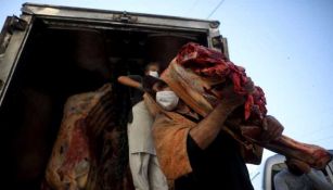 Un trabajador entrega una pieza de carne