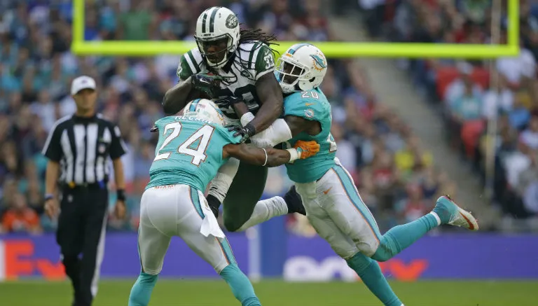 AP Chris Ivory entre dos defensivos de Miami