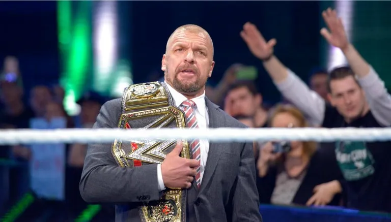 WWE.COM Triple H observa a Roman Reigns
