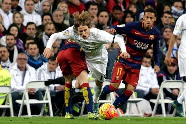 Dos jugadores del Barcelona cometiéndole una falta a Luka Modric