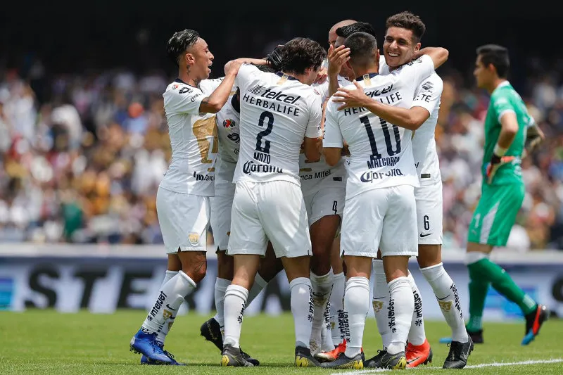 Jugadores de Pumas se abrazan tras una anotación a Chivas