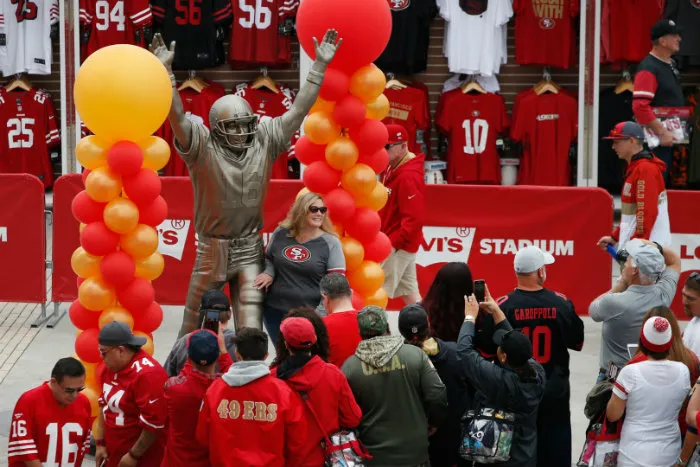 AP Fans posando con la estatua de Joe Montana