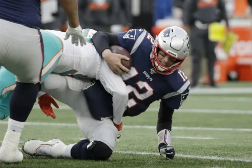 Tom Brady siendo tackleado por un jugador de los Dolphins