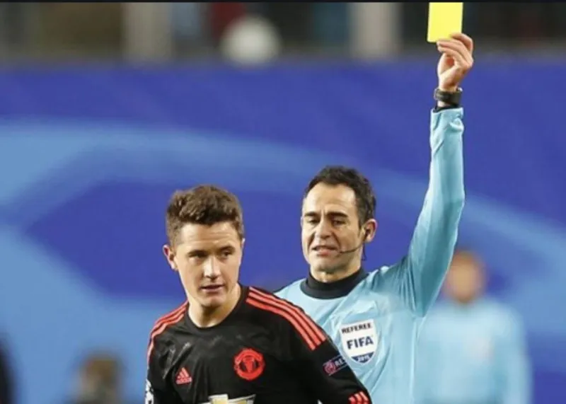 Carlos Velasco Carballo en su época de árbitro amonestando a un jugador