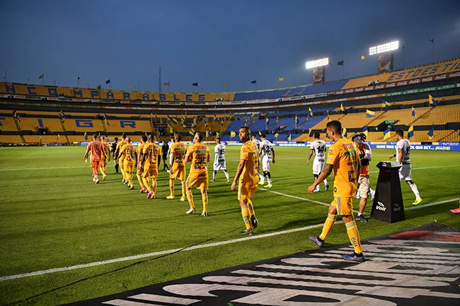 Jugadores de Tigres y Juárez entran al campo en un juego sin público