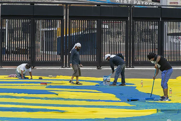Los integrantes de la Monumental pintando la manta