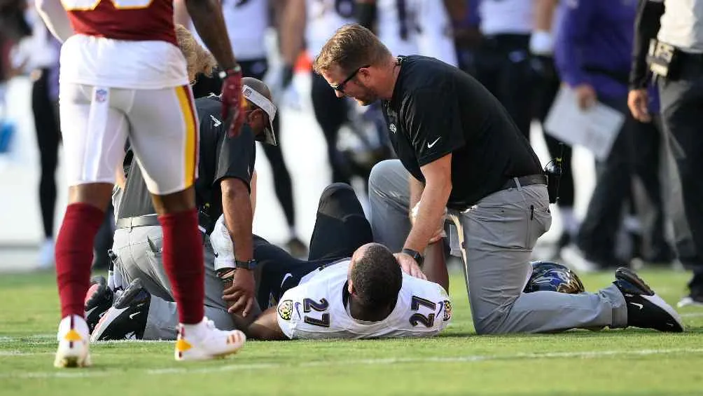 JK Dobbins siendo atendido en el terreno de juego