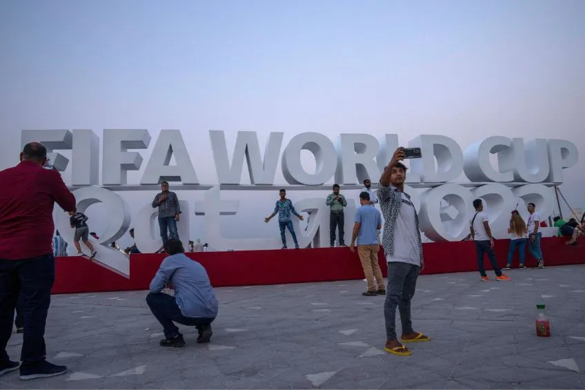 AP Turistas tomándose una foto en un letrero de Qatar 2022
