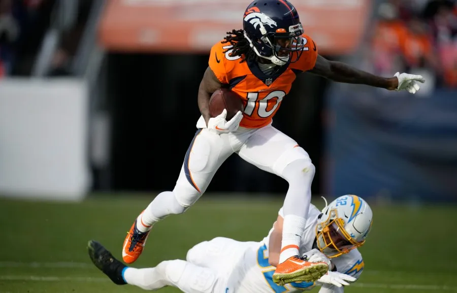 AP Jerry Jeudy acarrea el balón sobre jugador de Chargers