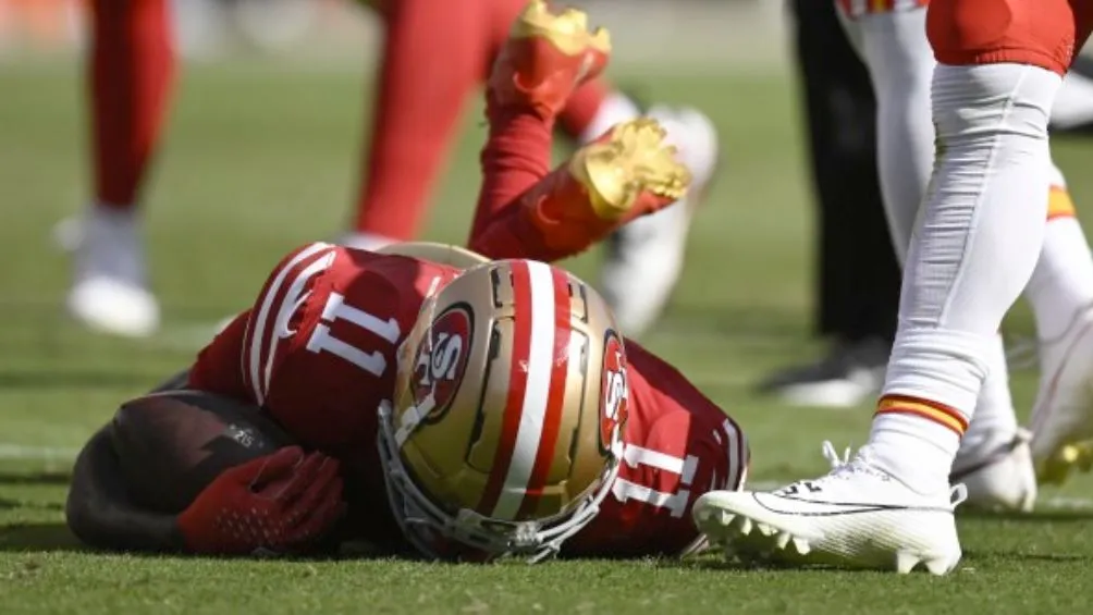 Brandon Aiyuk tendido en el campo