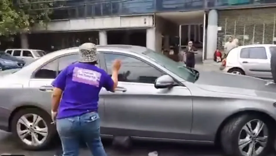 El bolso quedó por fuera del auto y una persona lo jaló / Redes Sociales