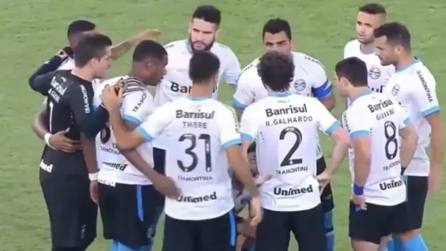 Los jugadores del Gremio en reunión, mientras Douglas orina en el campo