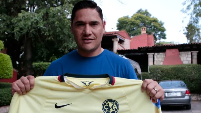 Moi sostiene una playera de las Águilas para la lente de RÉCORD