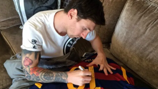 Messi, firmando la playera que obsequió a Ronaldinho