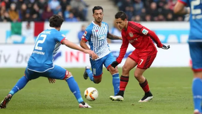 Chicharito toca el balón entre la marca de los defensas