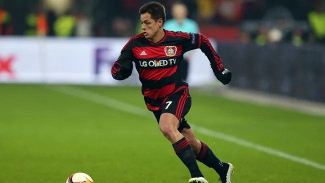 Chicharito conduce el balón en partido del Bayer