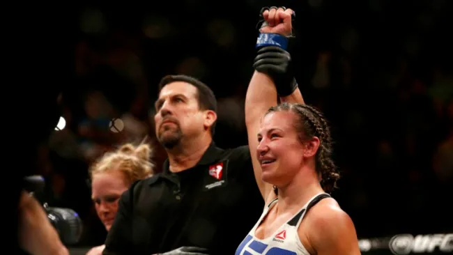El referee levanta la mano de Miesha Tate tras ganar a Holly Holm