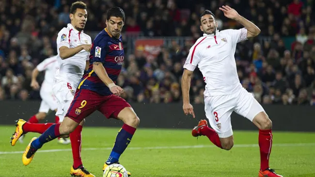 Luis Suárez disputa el balón en partido contra Sevilla