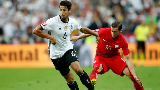 El mediocampista alemán, Sami Khedira, intenta salir jugando ante la marca de Grzegorz Krychowiak