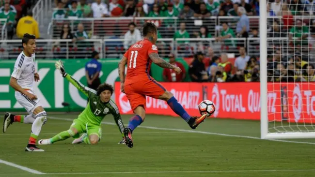 El delantero chileno Vargas define ante la mirada de Ochoa y Moreno