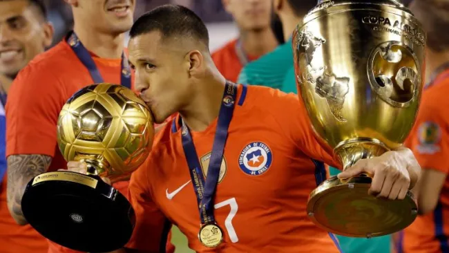 Alexis besa los trofeos obtenidos en la Copa América